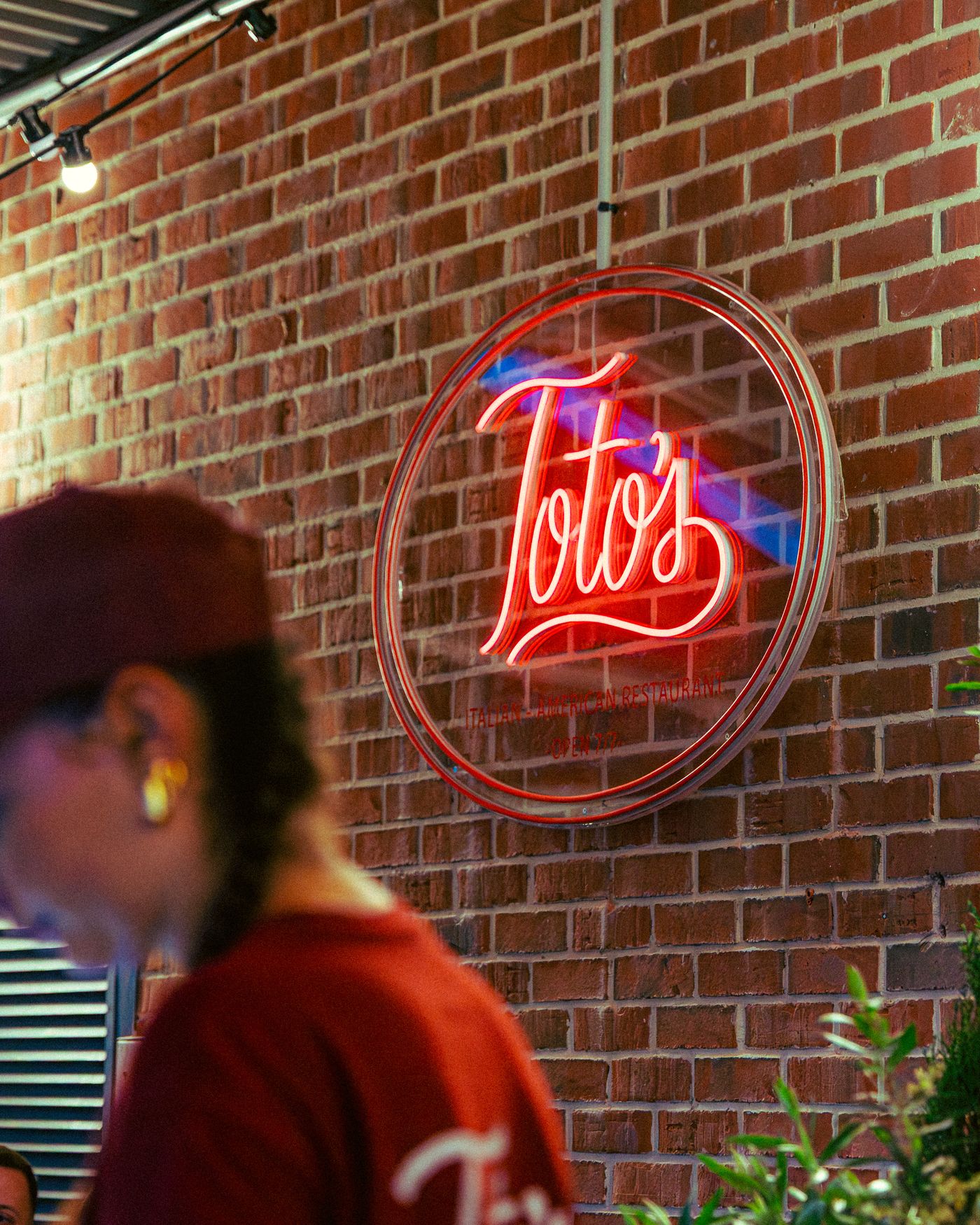 Le néon rouge Toto's sur le mur de briques du restaurant, ambiance New York